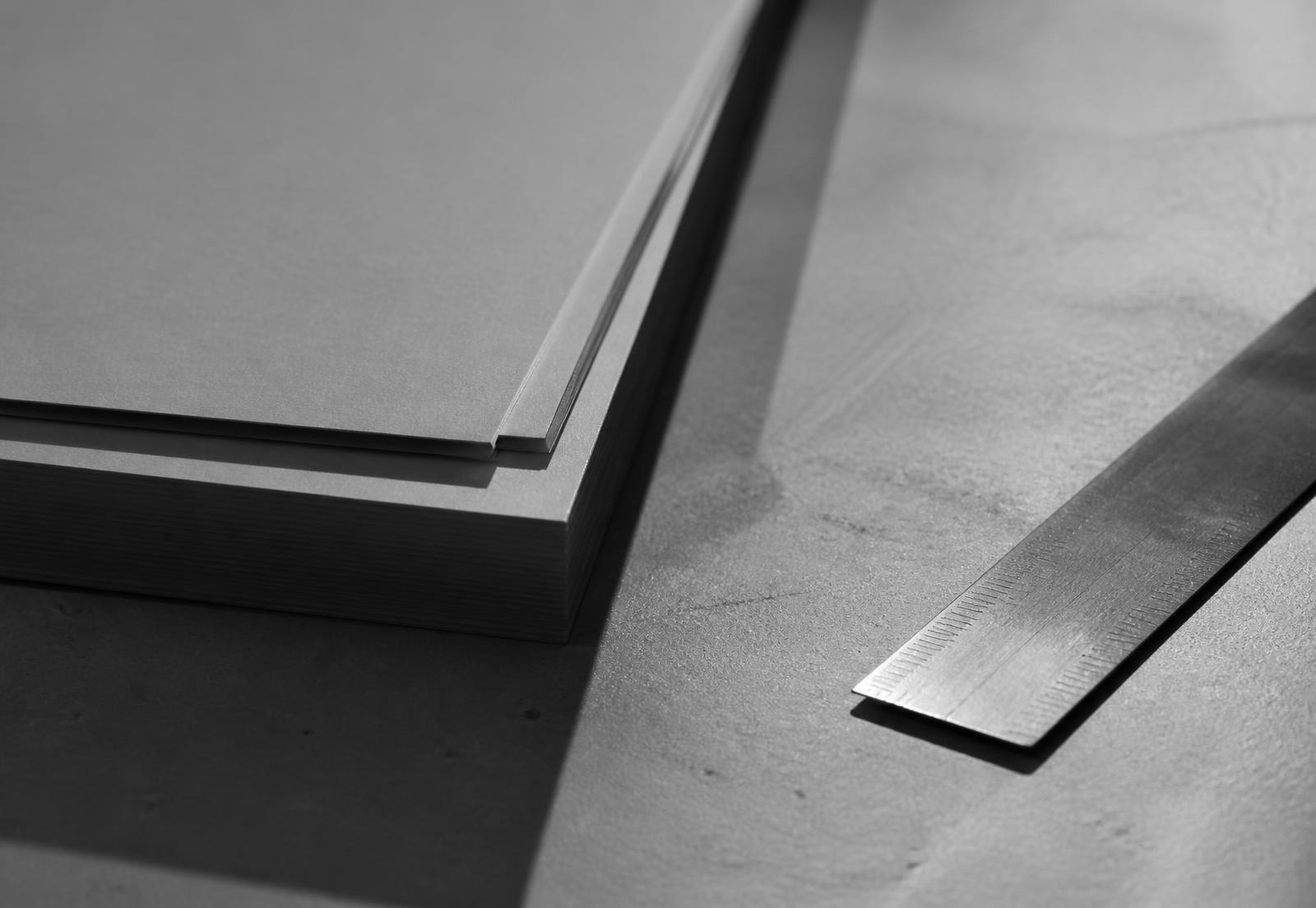 Feuilles de papier et règle métallique sous une lumière rasante